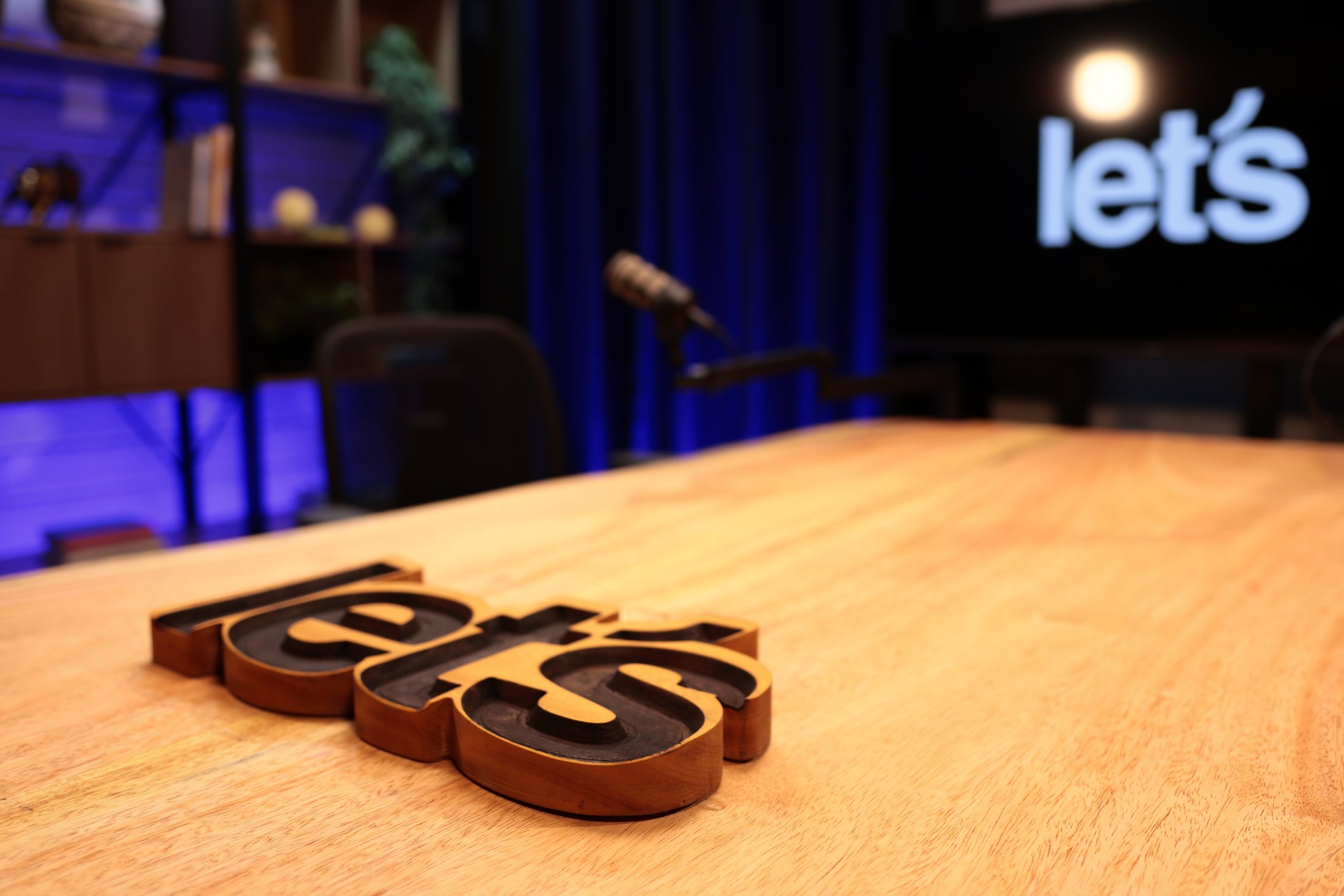 Mesa do estúdio da Let's Media com o logo let's em madeira