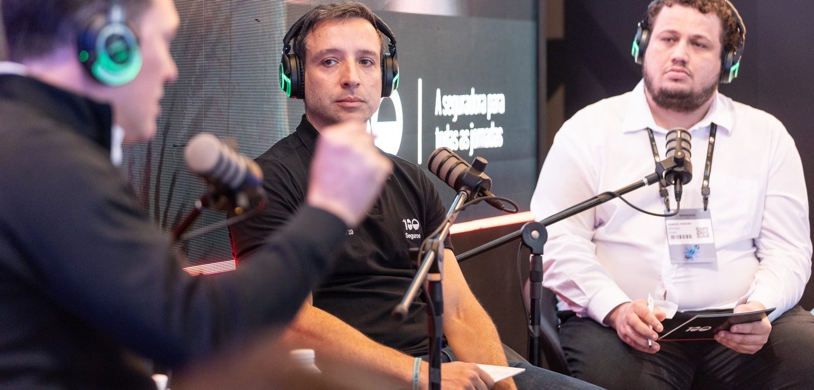 Set do 180Cast na Febraban Tech, três pessoas de fone e microfone em poltronas